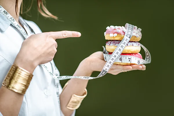 woman holding doughnuts with tape measure