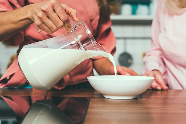 Pouring Fresh Milk into Bowl in Kitchen
