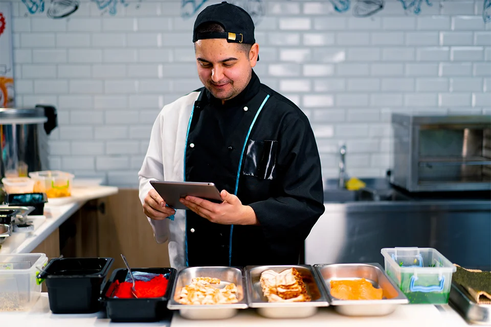 chef uses tablet in commercial kitchen setting